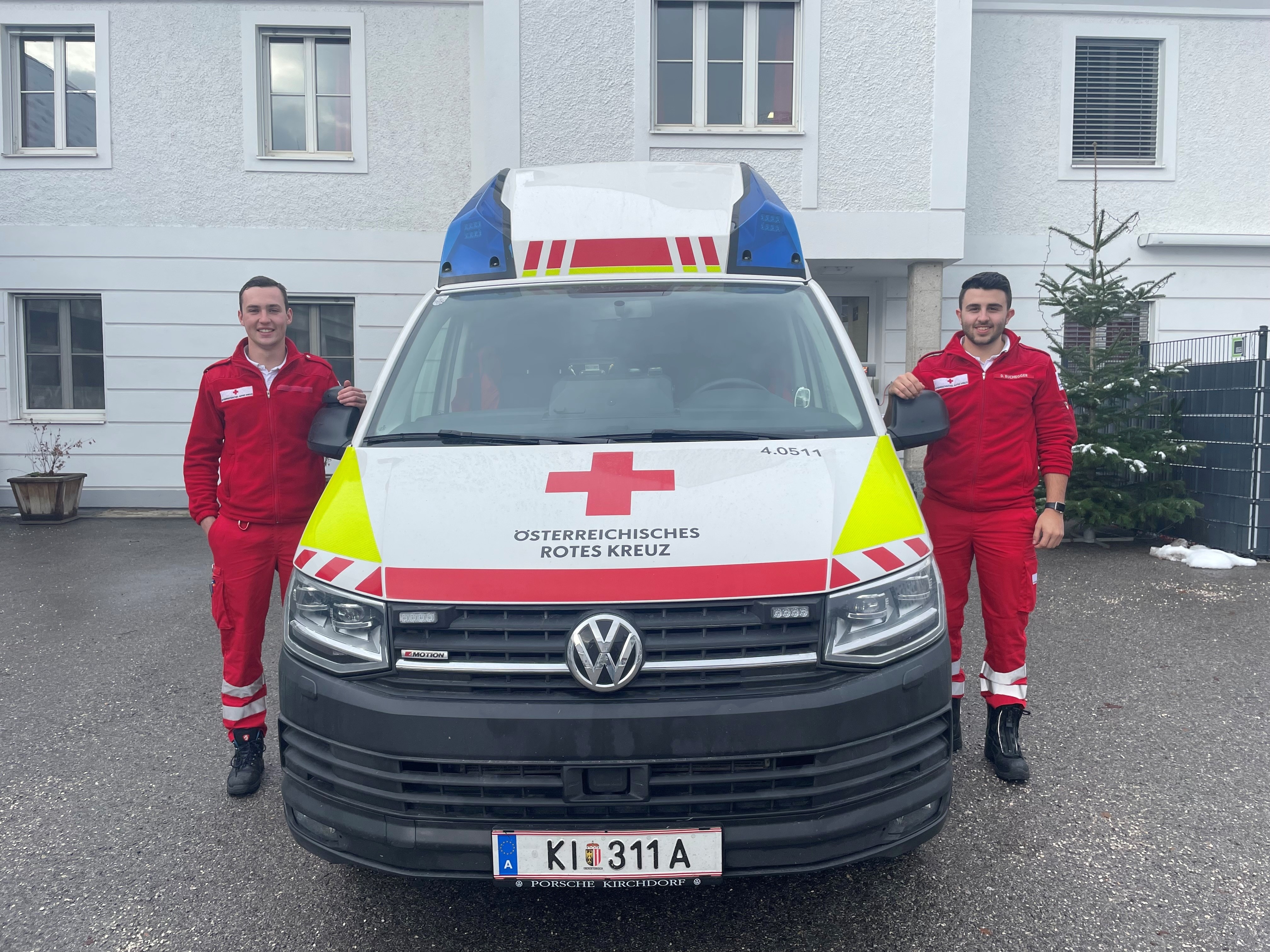 Zwei Zivildiener stehen rechts und links neben einem Rettungsauto