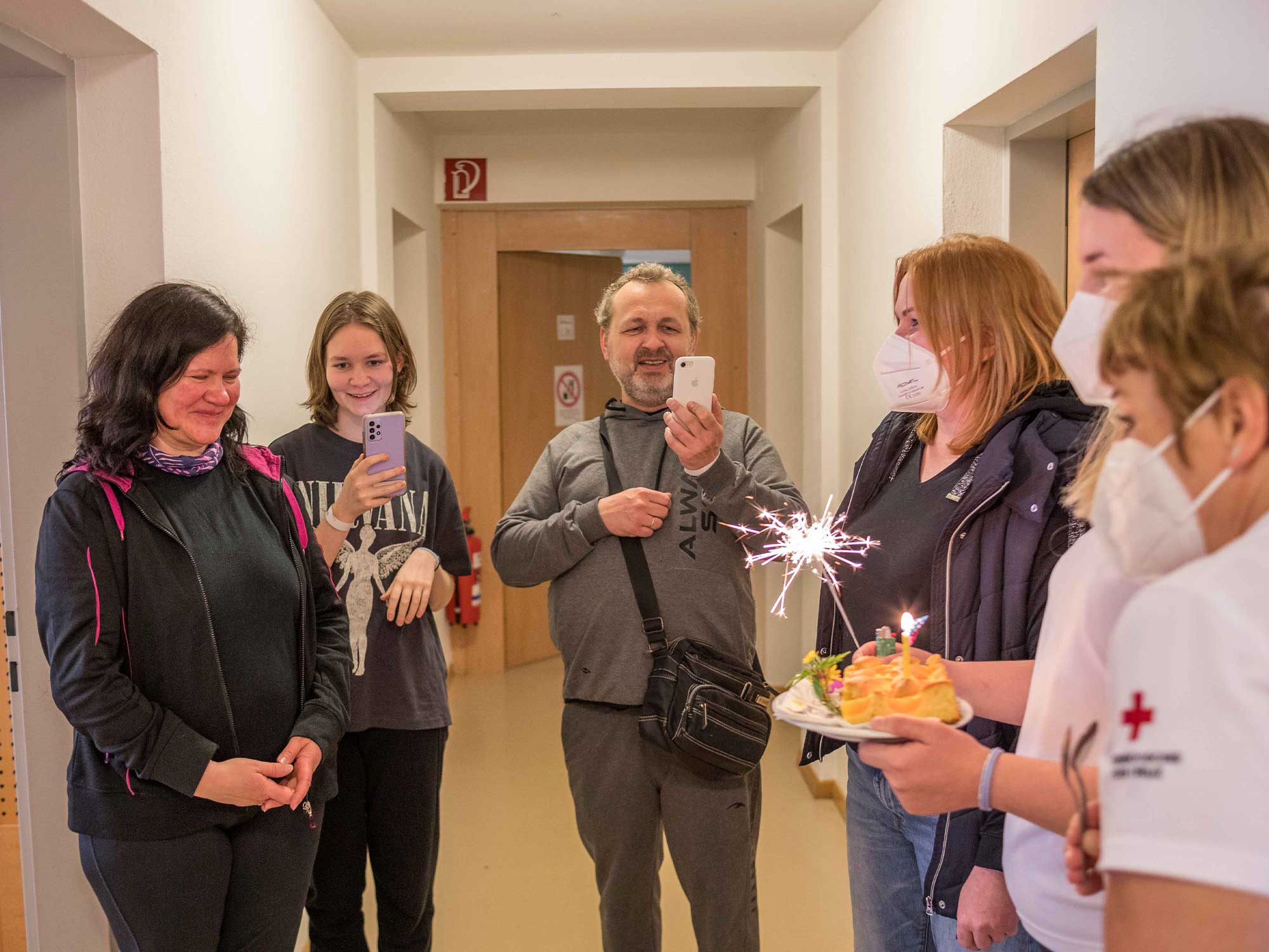 Gerade angekommen und noch gezeichnet von dem Erlebten wird diese geflüchtete Frau mit einem Geburtstagskuchen von den Rotkreuz-Mitarbeiter:innen empfangen.