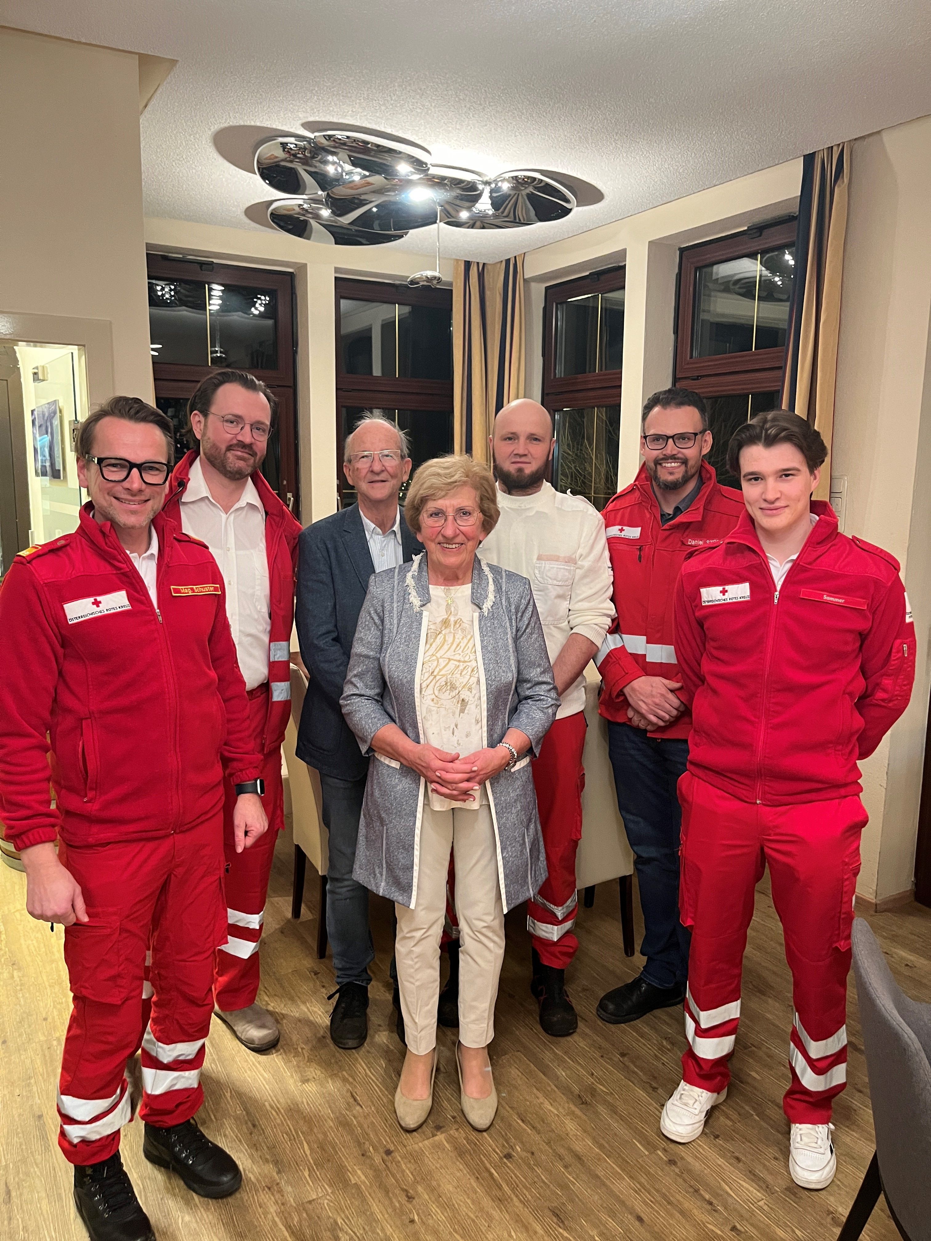 Ein Gruppenfoto mit Gitta Huber, ihrer Familie und Rettungsdienstmitarbeiter:innen aus Vöcklabruck