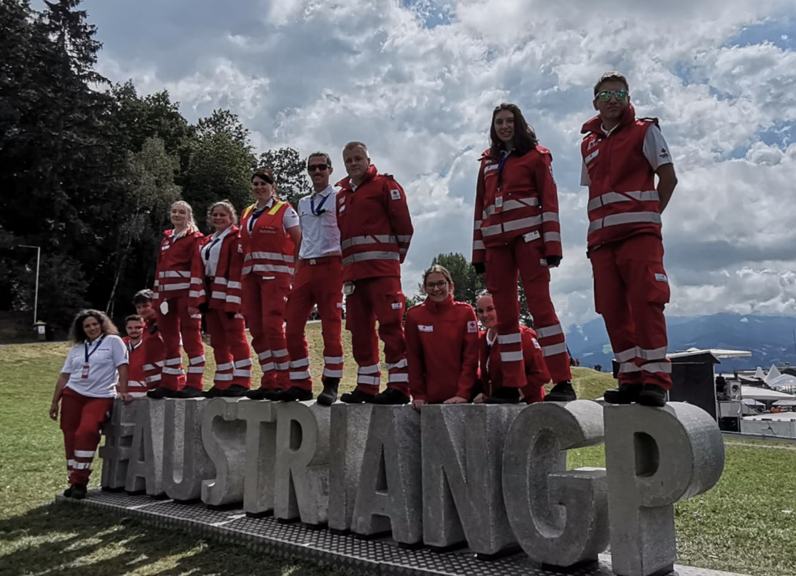 Formel 1 2022 - © M. Scheiber / Rotes Kreuz Knittelfeld Ein Team an Rotkreuz-Sanitäter:innen steht auf und neben einem #AustrianGP-Schiftzug aus Beton am Formel 1 Grand Prix 2022 in Spielberg.