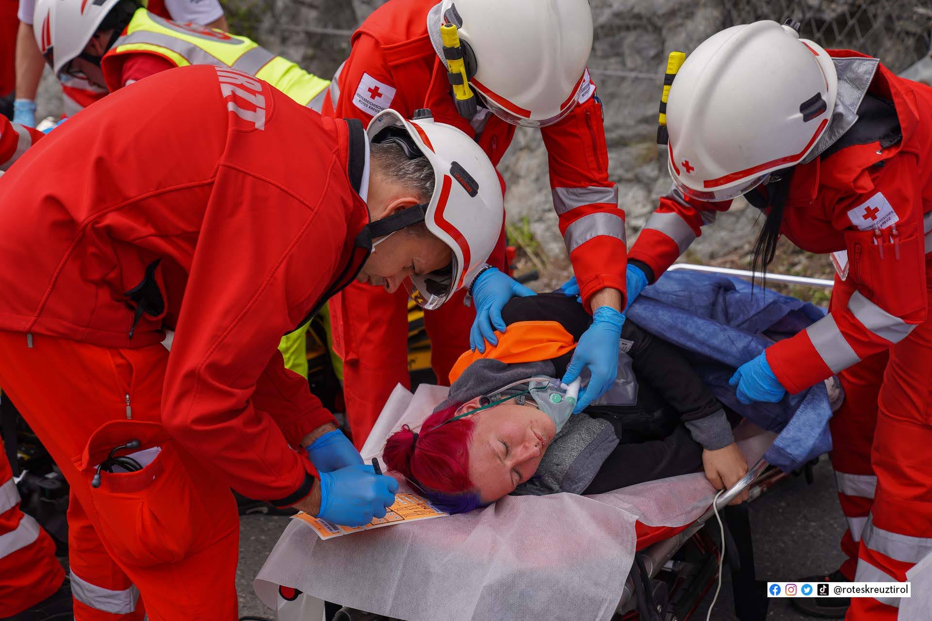 Zu sehen ist ein Einsatzgeschehen, bei dem vier Sanitäterinnen um eine verletzte Person stehen und diese fachgerecht versorgen